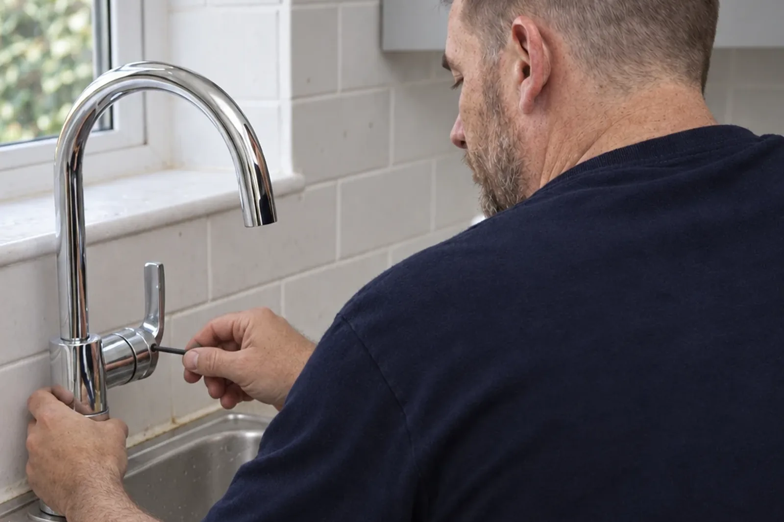 An IOT Homes plumber working on a kitchen mixer tap